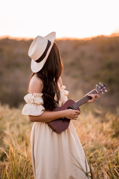 女人穿着白色的玩木吉他
